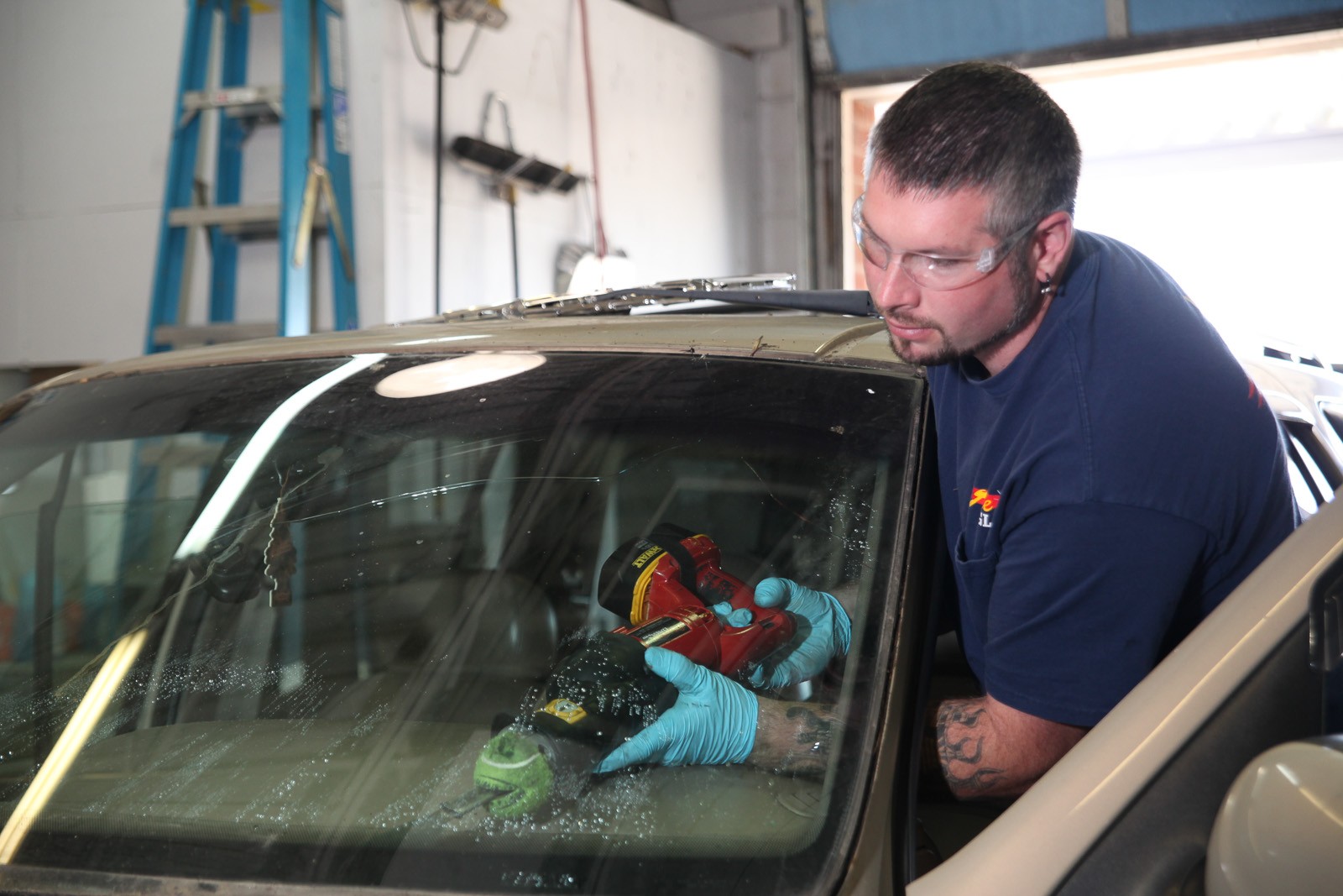 Technician in safety glasses repairing a cracked windshield