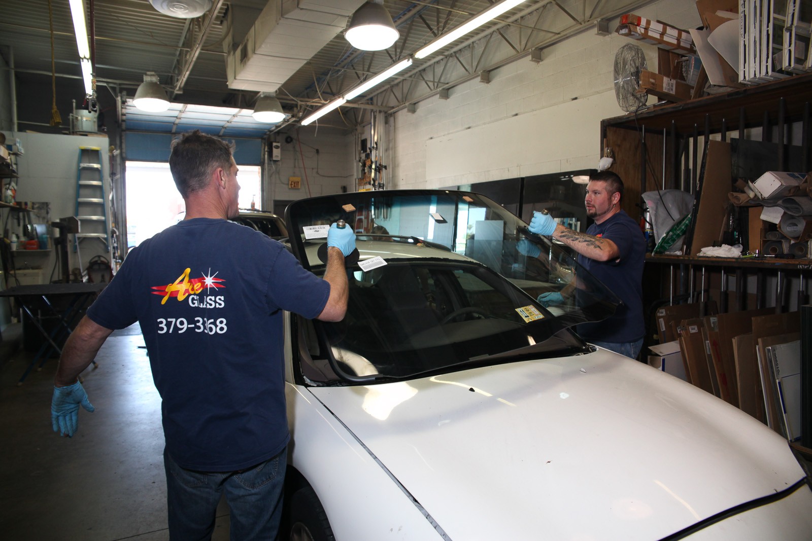 Two Ace Glass technicians installing a windshield in the shop